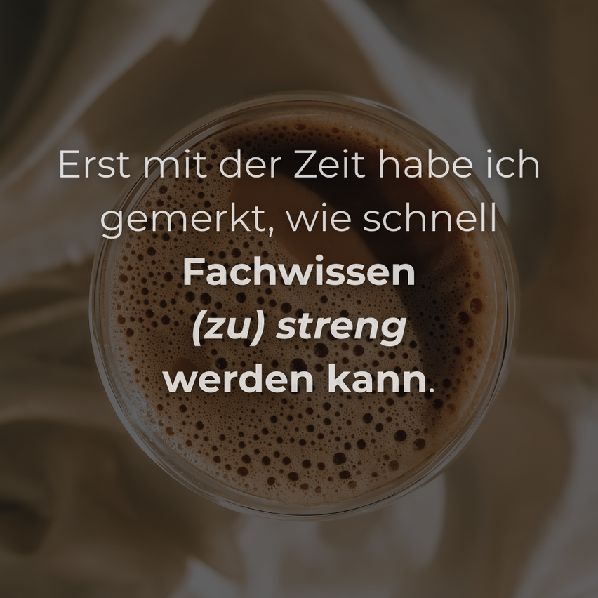 Ein Kaffeebecher mit einem Zitat darauf, das lautet: 'Erst mit der Zeit habe ich bemerkt, wie schnell Fachwissen (zu) streng werden kann.' Der Kaffee befindet sich in einem transparenten Glasbecher.
