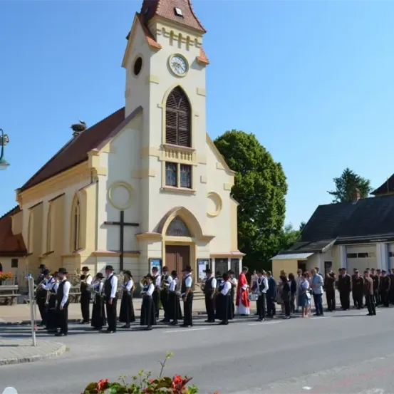 Eine Gruppe von Menschen in Uniform und Hüten steht vor einer Kirche. Einige spielen Musikinstrumente.
