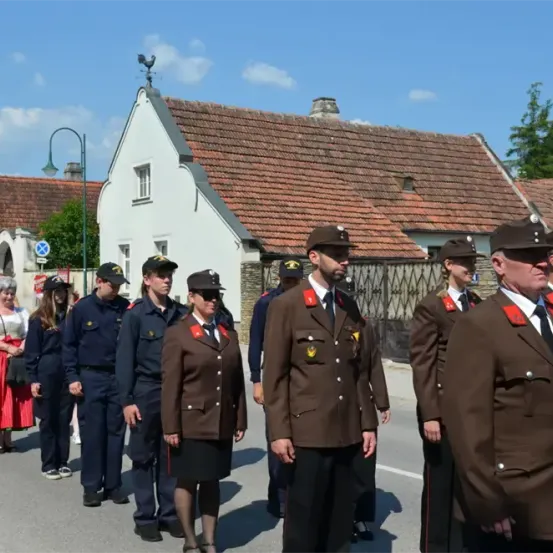 Eine Gruppe uniformierter Beamter steht vor einem Gebäude. Einige Leute gehen auf der Straße.
