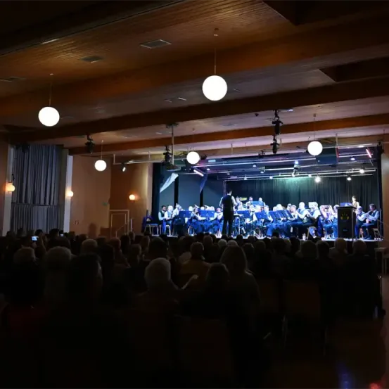 Eine Band spielt bei Nacht auf der Bühne vor einem Publikum in einem schwach beleuchteten Raum.