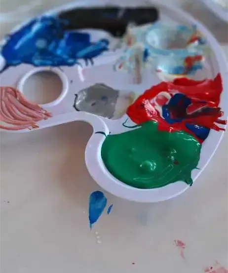 Eine Palette mit mehreren Farben, einschließlich Blau, Rot, Grün und Grau. Sie liegt auf einer weißen Oberfläche.