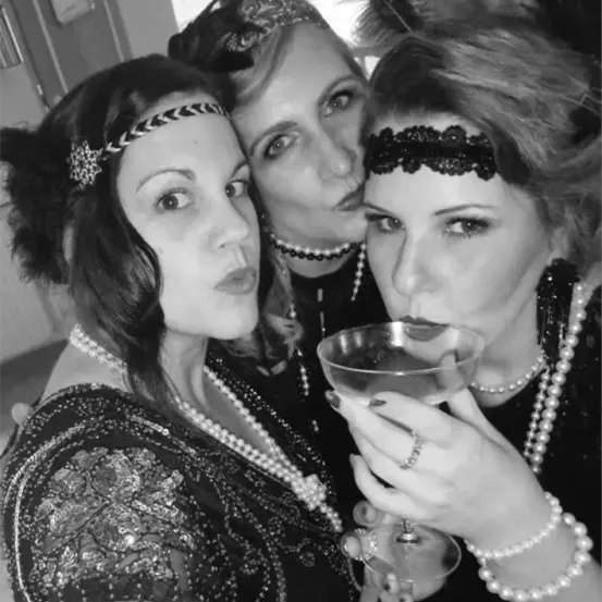 Drei Frauen in Flapper-Kleidung posieren für ein Selfie, eine hält ein Martiniglas.