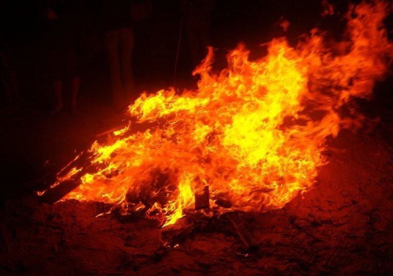 Ein Lagerfeuer brennt nachts hell und wirft ein warmes Licht. Es knackt intensiv heiß.