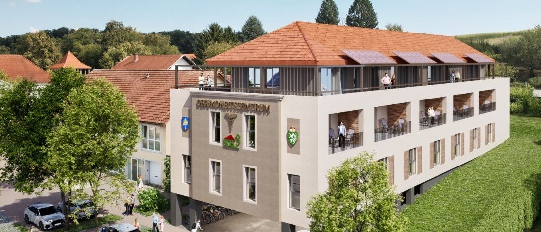 Ein Luftbild eines Gebäudekomplexes mit Solarpanels auf dem Dach. Es gibt Menschen auf den Balkonen und andere, die auf dem Parkplatz spazieren. Autos sind davor geparkt.