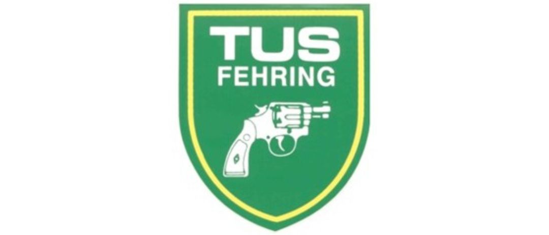 Das Bild zeigt einen grünen Schild mit weißem Text 'TUS FEHRING' und einer weißen Revolver-Symbol in der Mitte.
