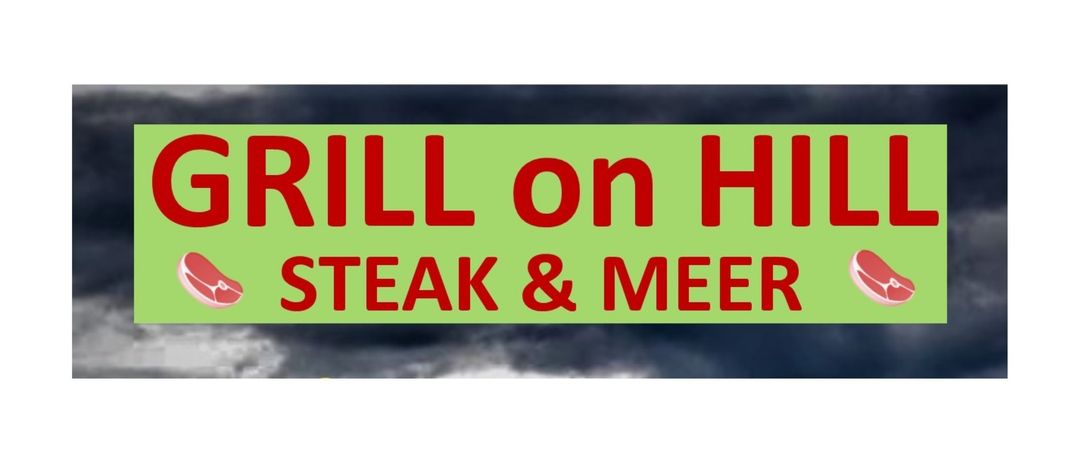 Ein Schild mit rotem Text auf grünem Hintergrund sagt 'GRILL auf HSTEAK & MEER'. Der Hintergrund ist dunkel und wolkenverhangen.