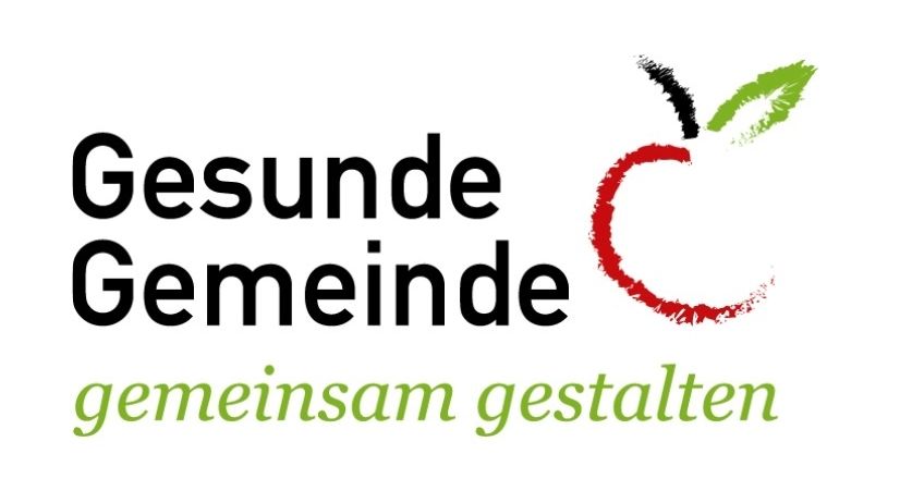 Das Logo von Gesunde Gemeinde zeigt einen roten Apfel mit einem grünen Blatt in fetten schwarzen Buchstaben. Der Text lautet 'Gesunde Gemeinde' und 'gemeinschaft gestaltet'.