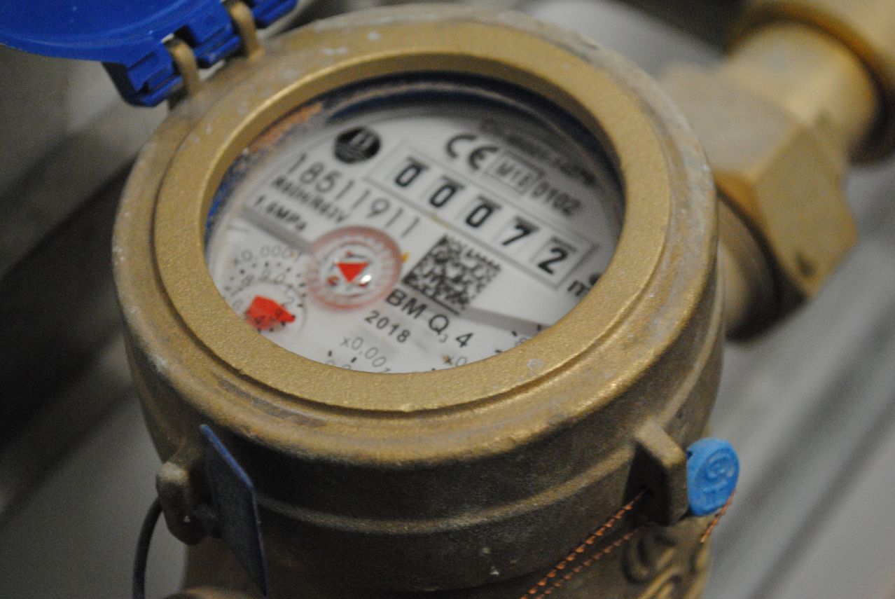 Eine Nahaufnahme eines Wasserzählers mit goldenem Rahmen. Der Zähler zeigt die Nummer 00072 und hat einen kleinen QR-Code. Das Datum ist 2018 Q4.