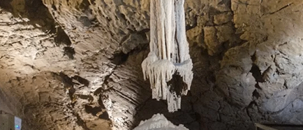 Eine große Höhle mit einer großen Stalaktit, die von der Decke hängt. Die Höhle hat eine felsige Oberfläche und einige Steine auf dem Boden.