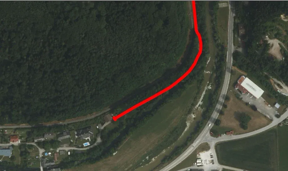 Luftaufnahme eines bewaldeten Gebiets mit einer roten Linie, die einen Pfad anzeigt, neben einer Straße mit Gebäuden und einem Pool.