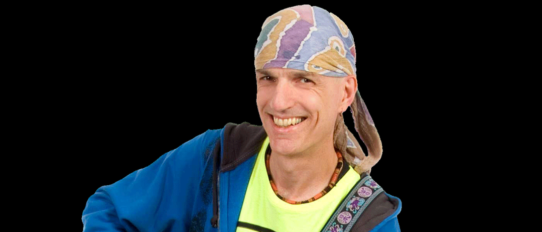 Eine Person steht und hält eine Gitarre. Die Gitarre hat einen schwarzen Korpus und einen weißen Kopf. Die Person trägt eine blaue Jacke und ein grünes Shirt.