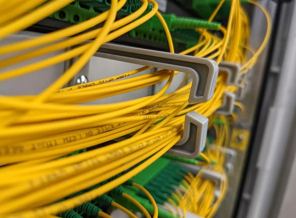 Ein Nahaufnahme eines Serverraums mit gelben Kabeln, die an einen Server angeschlossen sind und durch Kabelbinder organisiert werden.