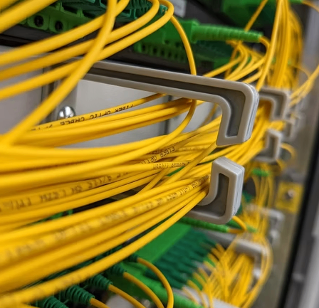 Ein Nahaufnahme eines Serverraums mit gelben Kabeln, die an einen Server angeschlossen sind und durch Kabelbinder organisiert werden.