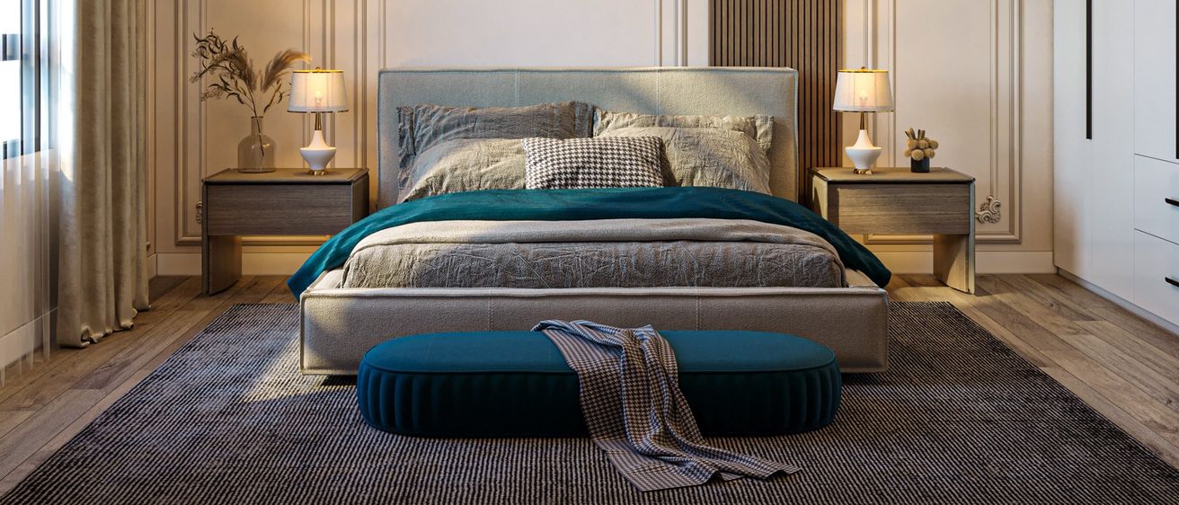 Ein elegant eingerichtetes Schlafzimmer mit einem großen Bett, zwei Nachttischen und einem dekorativen Teppich. Das Bett ist mit einer türkisen Decke bedeckt und hat verschiedene Kissen. Der Raum hat Holzböden und klassische Wanddesigns.