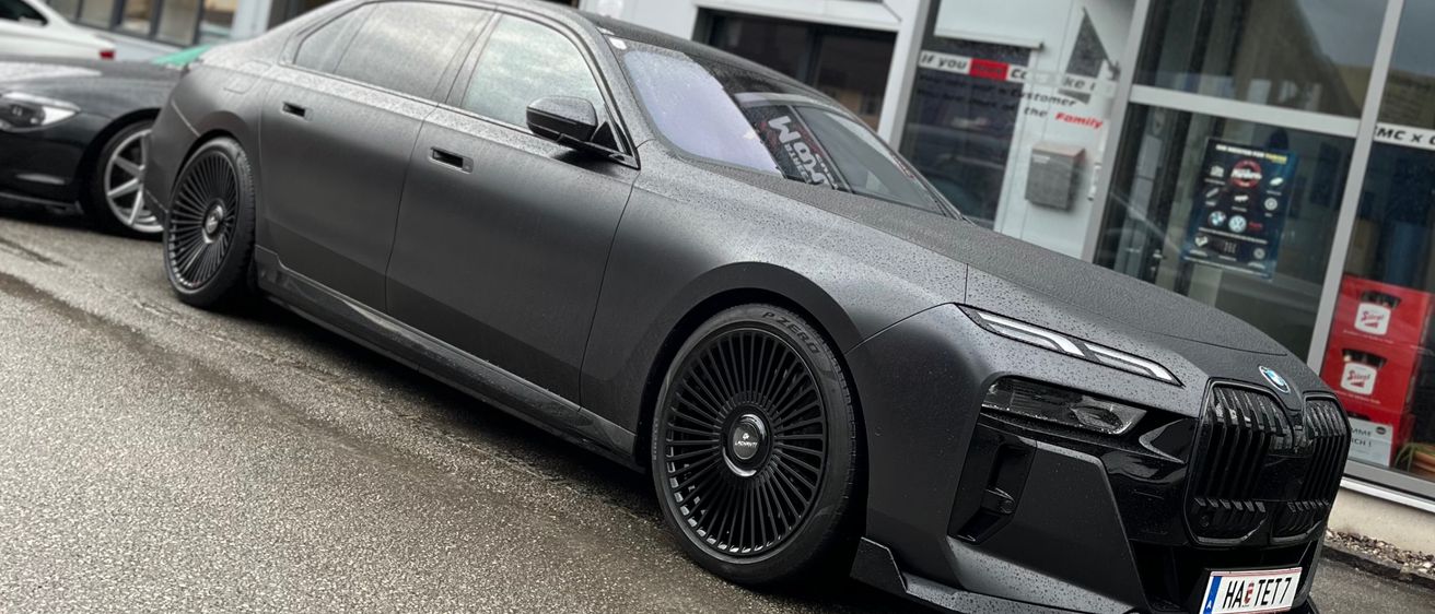 Ein schwarzer BMW 7er ist vor einem Gebäude mit einem Schild, das Street Markers Customs sagt, geparkt.