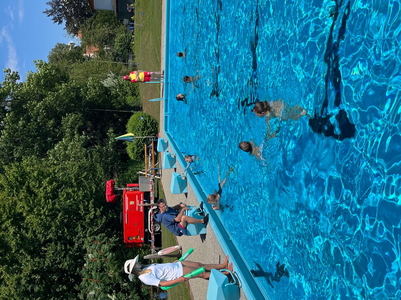 Eine oberirdische Ansicht eines Schwimmbeckens mit mehreren Schwimmern und zwei Rettungsschwimmern, die an der Seite sitzen.