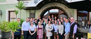 Eine Gruppe von Menschen steht vor einem Gebäude mit dem Schild 'Schwarzer Bar'. Sie alle lächeln und scheinen für ein Foto zu posieren.