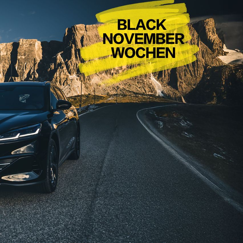 Ein schwarzer SUV fährt auf einer Bergstraße. Die Worte Black November Wochen sind in Gelb oben angezeigt.