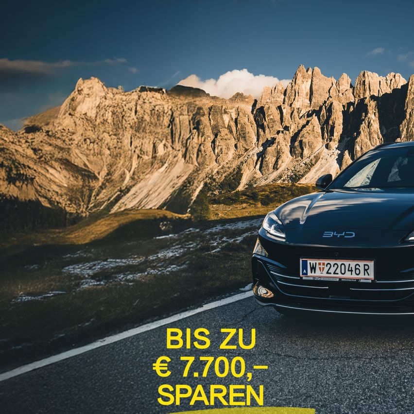 Ein schwarzes Auto mit dem Kennzeichen 'W 22046R' steht auf einer Bergstraße mit dem Text 'BIS ZU € 7.700, SPAREN'.