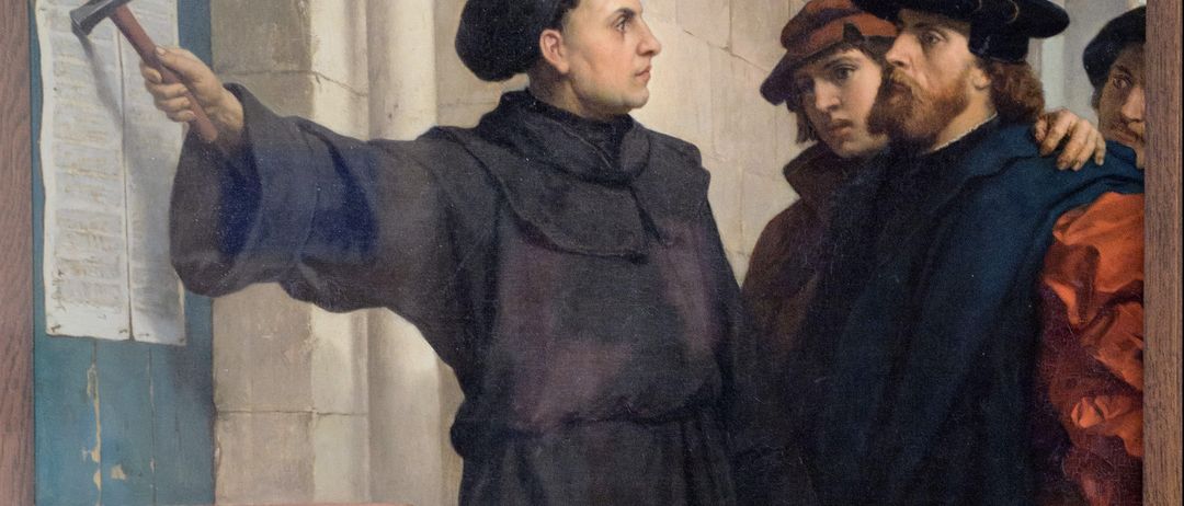 Ein Gemälde zeigt einen Mann in einer schwarzen Robe, der zeigt, neben zwei bärtigen Männern in Hüten, einer in einem braunen Mantel, vor einer Steinmauer.