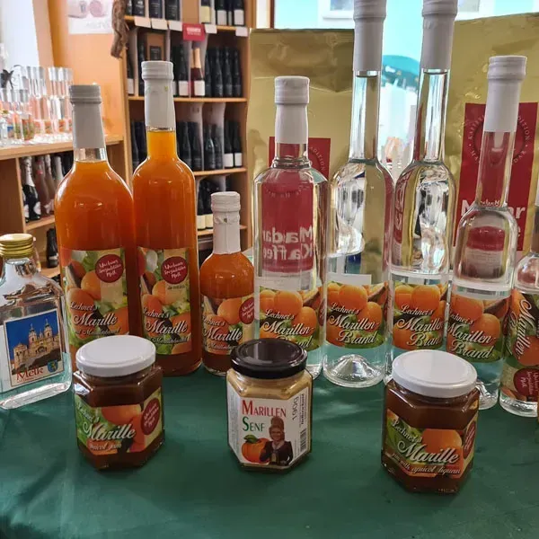 A table displays various Marille products, including bottles of liqueur, jam, and a small bottle of liqueur. The bottles are labeled with the brand name Marille.