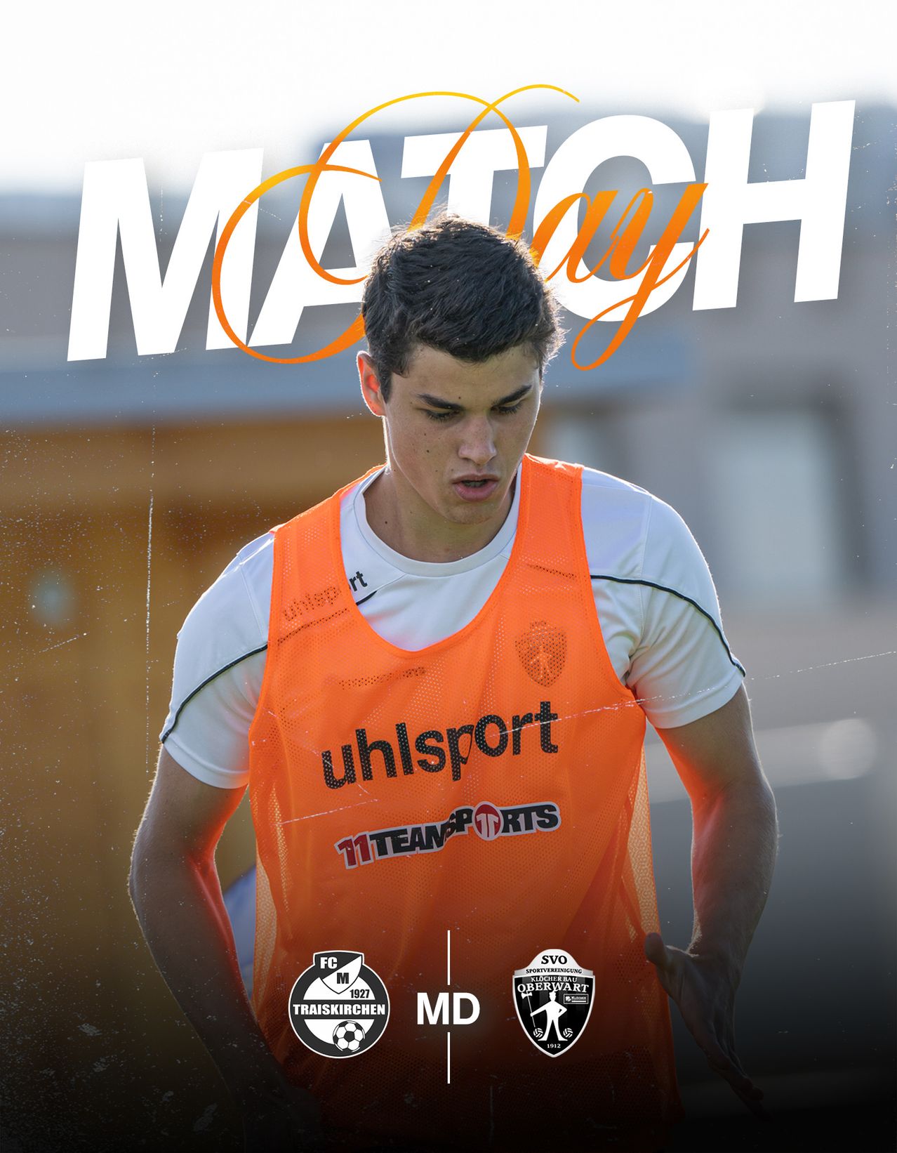 Ein männlicher Fußballspieler in einem orangefarbenen Trikot mit dem Aufdruck uhlsport schaut nach links. Der Text 'MATCH DAY' ist im Hintergrund.