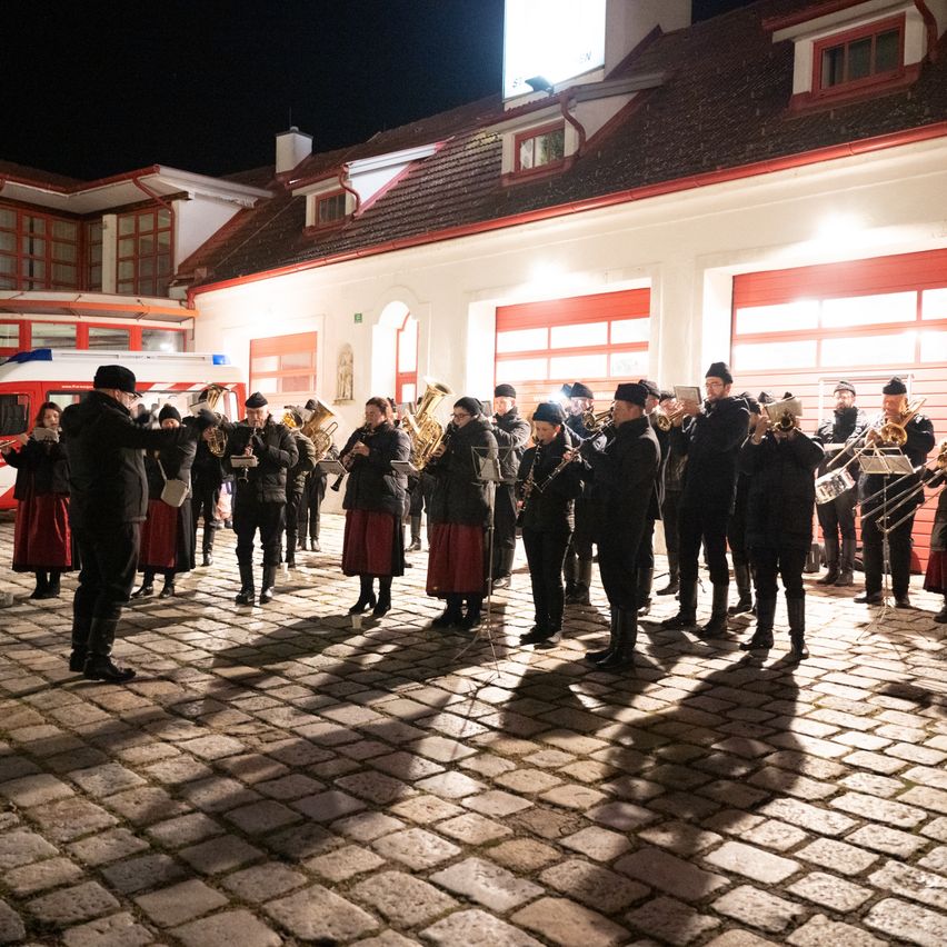 Eine Brass Band spielt nachts auf einer Kopfsteinpflasterstraße vor einem Gebäude mit rotem Rand.