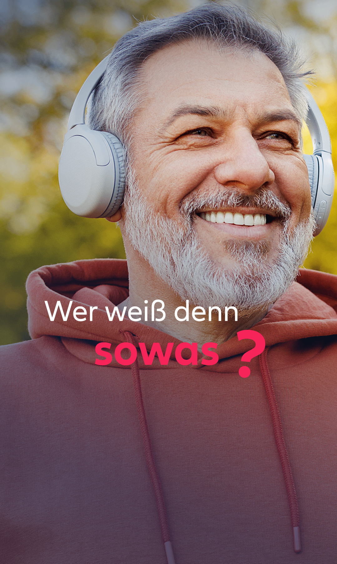 An older man with a beard and a hoodie smiles while wearing headphones. The image features a question mark and text in German.