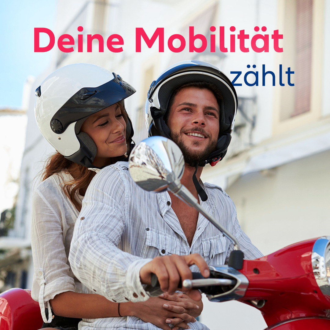 A couple on a red scooter, both wearing helmets, smiling and looking at each other. The background features a building with the text 'Deine Mobilität zahlt'.