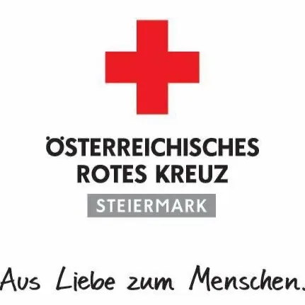 Das Emblem des Österreichischen Roten Kreuzes mit einem roten Kreuz und deutschem Text. Der Text übersetzt 'Aus Liebe zum Menschen'.