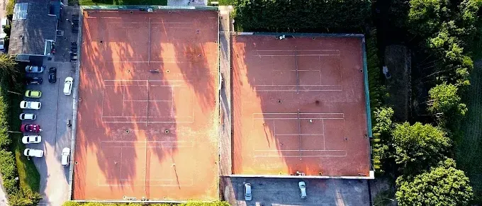 Eine Luftaufnahme eines Tennisplatzes mit Spielern, umgeben von Bäumen und Autos.