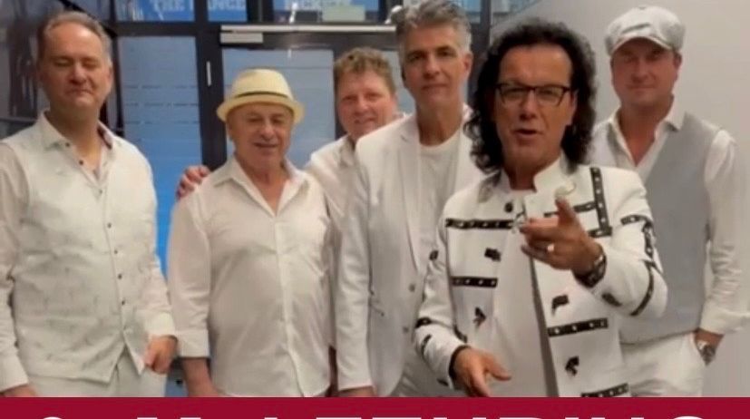 Eine Werbung für ein Konzert von Die Paldauer am 9. Mai. Fünf Männer in weißen Outfits posieren für ein Foto, einer zeigt auf die Kamera. Der Text enthält Ticketinformationen.