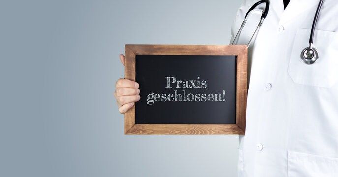 Ein Arzt in einem weißen Kittel hält ein Tafel mit der Aufschrift 'Praxis geschlossen!'. Der Arzt trägt ein Stethoskop.