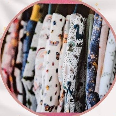 Eine Sammlung von Kinderpyjamas mit verschiedenen Aufdrucken, darunter Schmetterlinge, Sterne und Dinosaurier, auf einem Kleiderständer präsentiert.