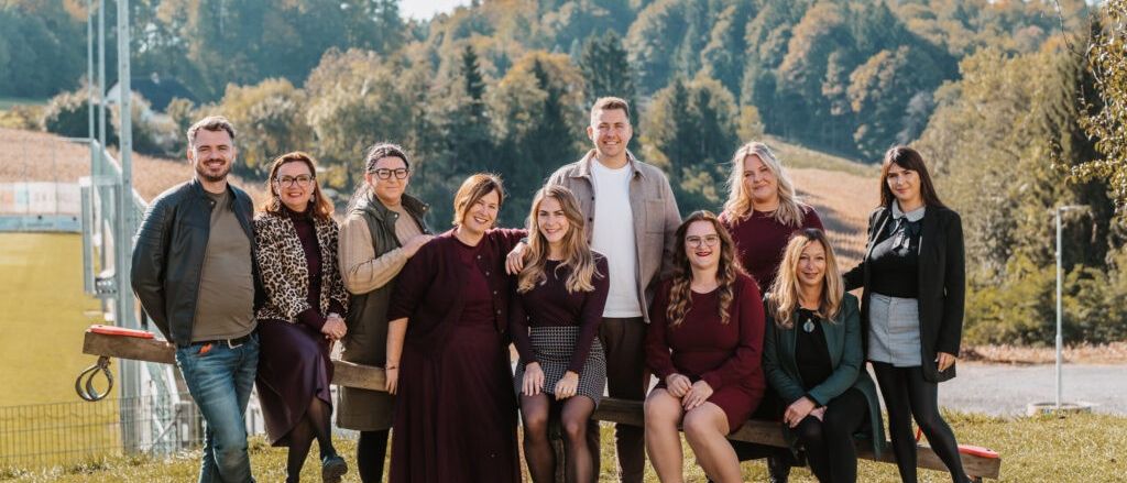 Eine Gruppe von Erwachsenen posiert für ein Foto im Freien mit Bäumen im Hintergrund.