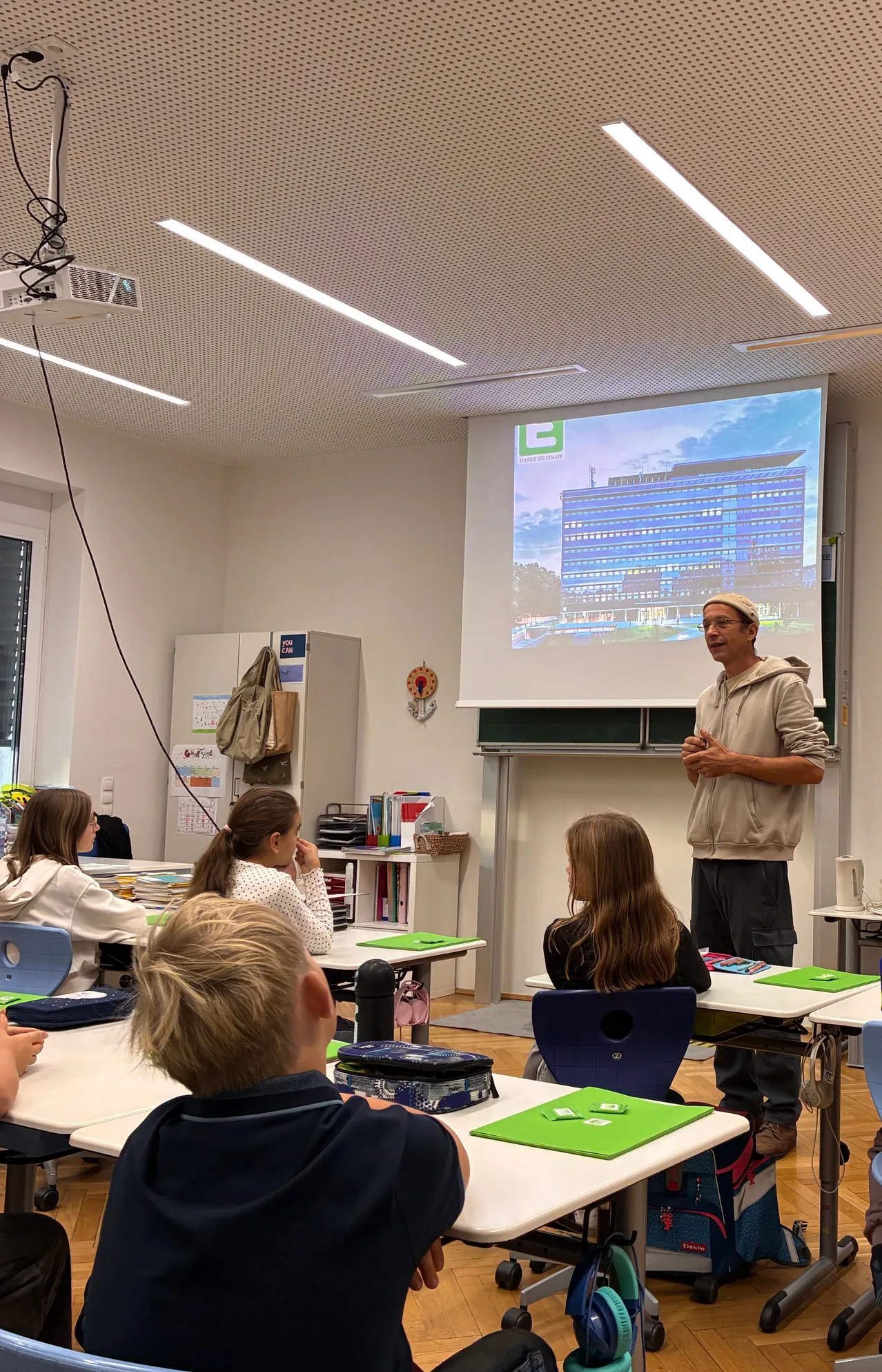 Ein Mann hält eine Präsentation für eine Gruppe von Kindern in einem Klassenzimmer.