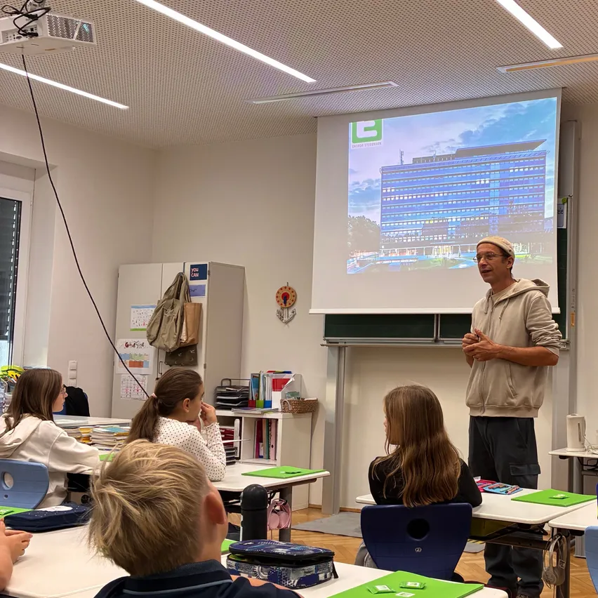 Ein Mann hält eine Präsentation für eine Gruppe von Kindern in einem Klassenzimmer.