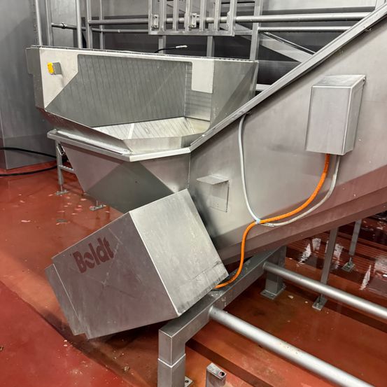 Industrieller Edelstahlausrüstung, mit 'Beldt' beschriftet, auf einem roten Boden geneigt mit Metallstützen und Kabeln.