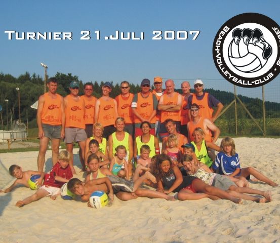 Gruppenfoto einer Volleyballmannschaft am Strand am 21. Juli 2007, mit Personen in orangen und gelben Westen und einem Volleyball in der Mitte.