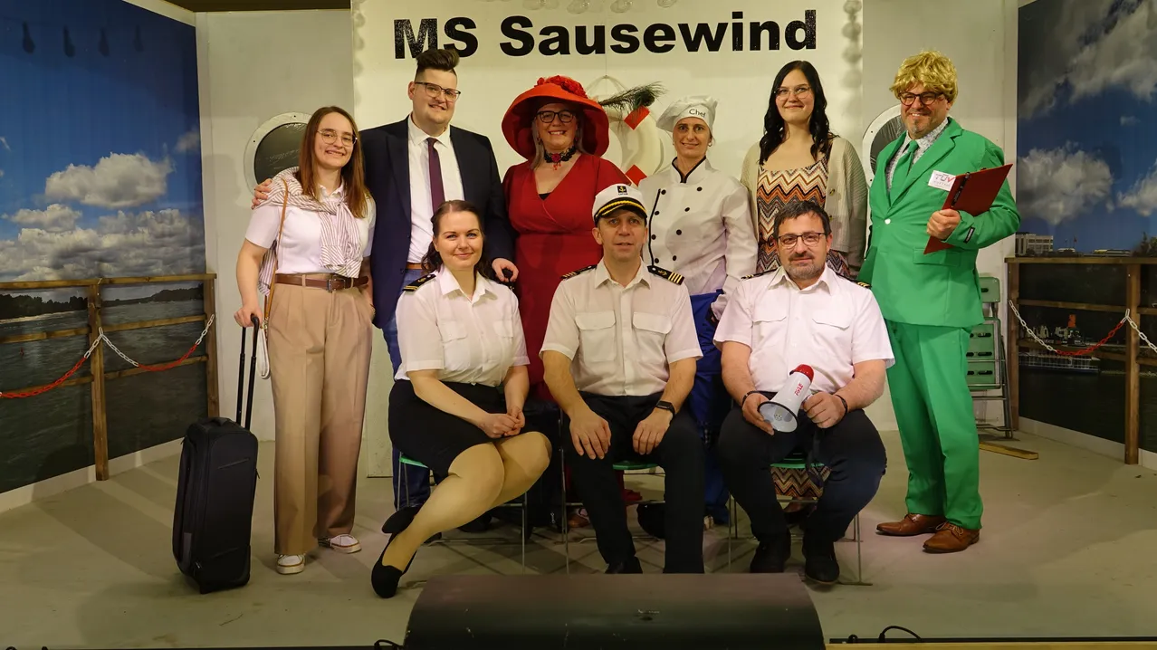 Eine Gruppe von Menschen in Uniformen und Hüten posiert für ein Foto vor einem Hintergrund mit der Aufschrift MS Sausewend.