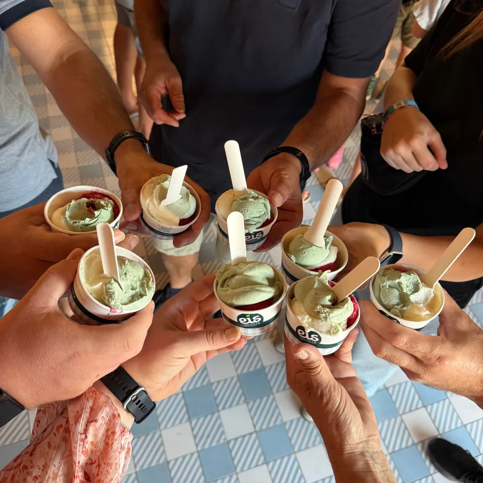 Eine Gruppe von Menschen hält mit Löffeln Tassen grünen Eis mit einer weißen und grünen Wirbel.