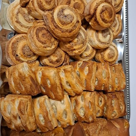 Ein Tablett gefüllt mit verschiedenen Gebäckstücken, darunter Croissants, dänisches Gebäck und Blätterteig, ordentlich angeordnet.