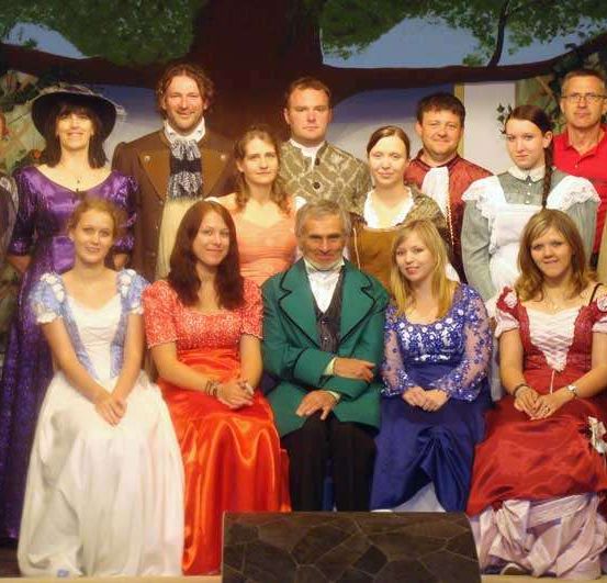 Eine Gruppe von Menschen in historischen Kostümen posiert für ein Foto auf der Bühne.