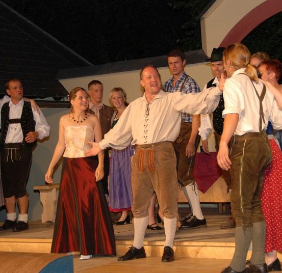 Eine Gruppe von Menschen in traditioneller Kleidung auf der Bühne bei Nacht, die einen Tanz ausführen.