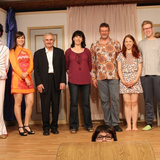 Eine Gruppe von Menschen in Kostümen posiert für ein Foto auf der Bühne.