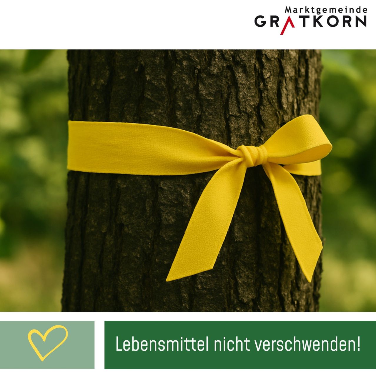 Ein Baumstamm mit einem gelben Band darum. Darunter sind ein Herzsymbol und der Text 'Lebensmittel nicht verschwenden!' zu sehen.