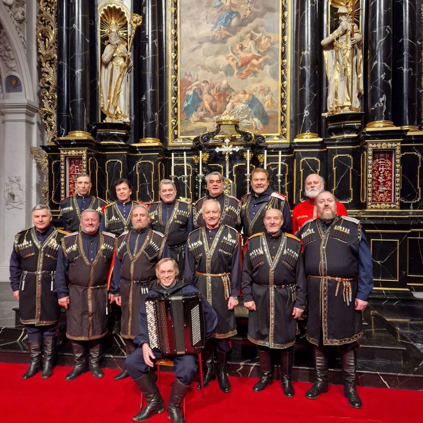 Eine Gruppe von Männern in traditionellen Uniformen, darunter einer, der ein Akkordeon spielt, posiert für ein Foto vor einem Kirchenaltar.