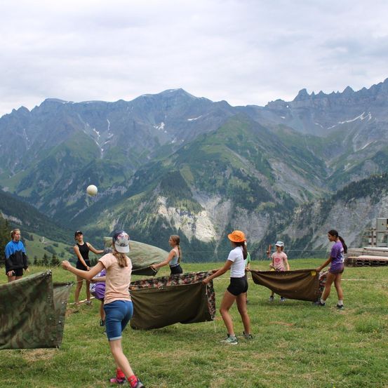 Eine Gruppe junger Leute spielt ein Spiel mit einem Ball in den Bergen. Sie halten ein Netz und versuchen, den Ball zu fangen.