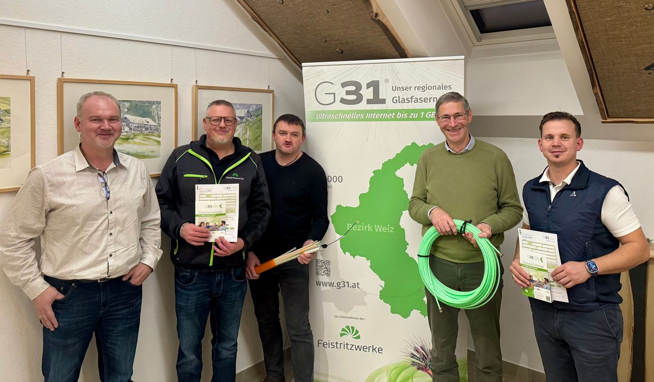 Drei Männer stehen vor einem Plakat für Hochgeschwindigkeits-Internet und halten ein Zertifikat und eine Spule mit grünem Kabel.