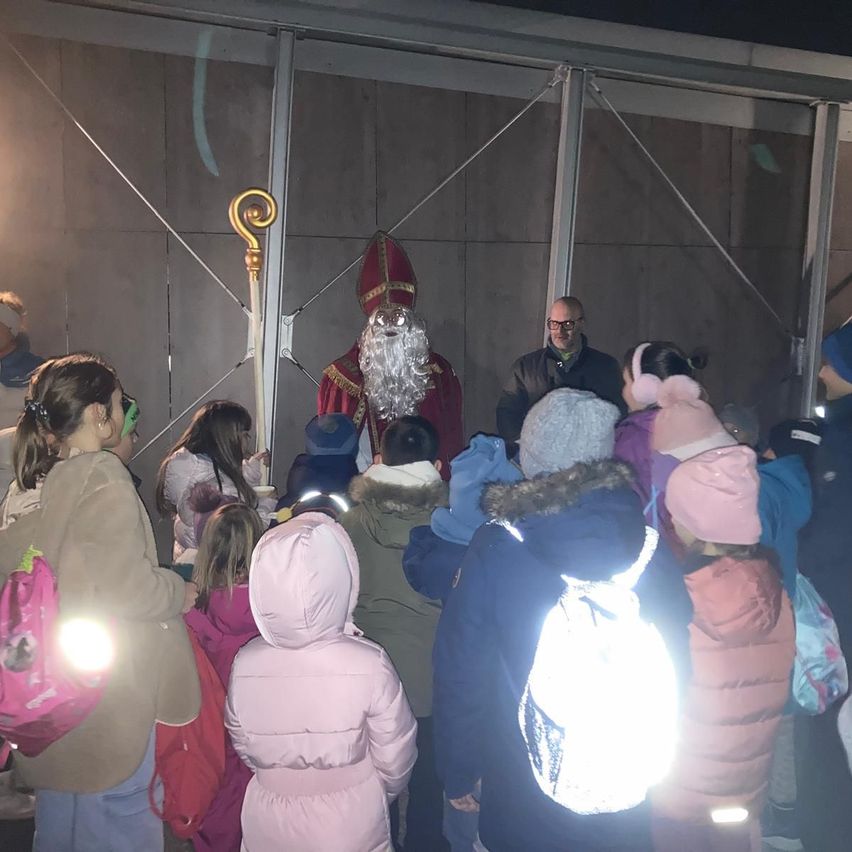 Eine Menschenmenge, darunter Kinder, versammelt sich um einen Mann in Santa-Claus-Verkleidung, der vor einer Metallkonstruktion steht.